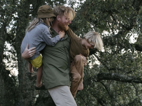 Image shows artist Ryan Board engaging with local children outdoors in Portugal