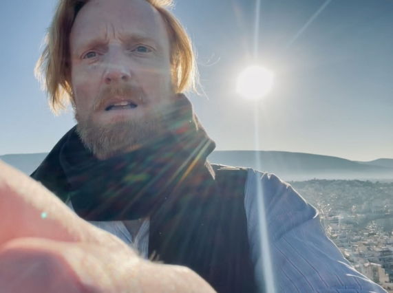 Image shows artist Ryan Board filming outdoors above Athens during 2025
