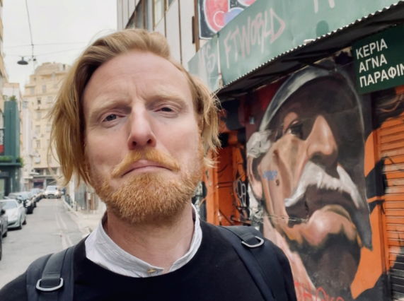 Image shows Artist Ryan Board on location filming his Reawakening Creativity series in Athens street